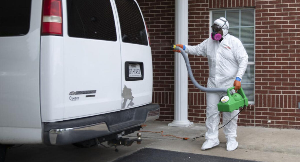Man in protective suit sanitizing white van