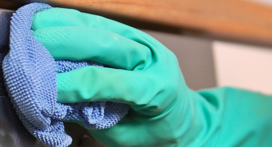 image of a gloved hand with a rag, sanitizing high-touch surface