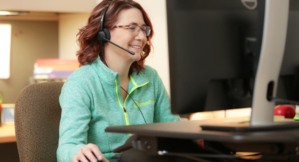 Friendly MUI team member smiling with phone headset in front of computer