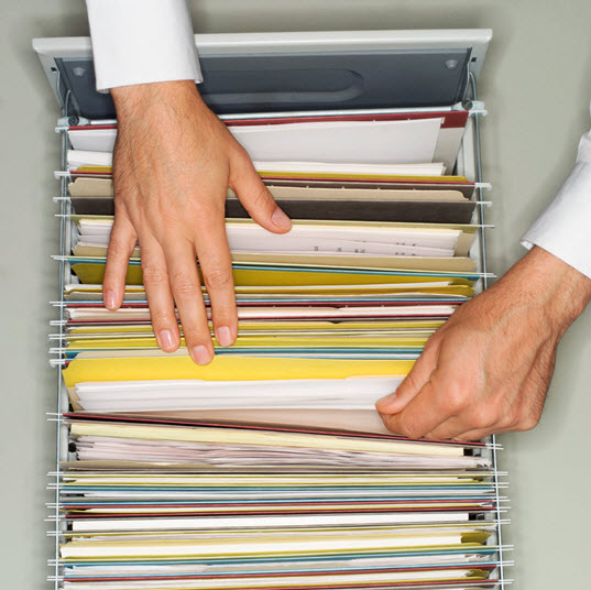 Hand on folders in filing cabinet