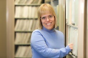 Smiling woman standing by wall of files