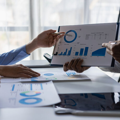 Business teams brainstorming with others using printed charts and graphs. Close-up pictures