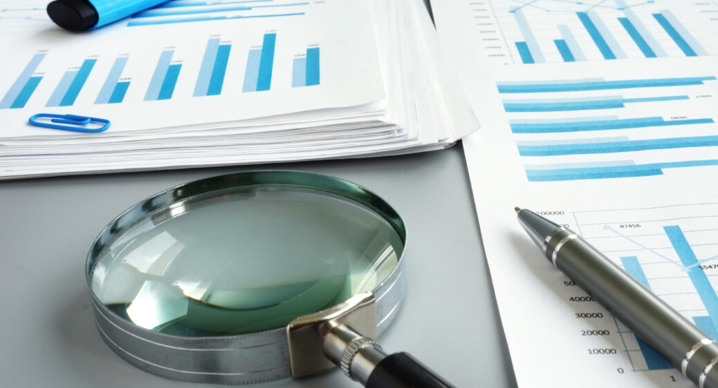 Magnifying glass and business report for auditing.