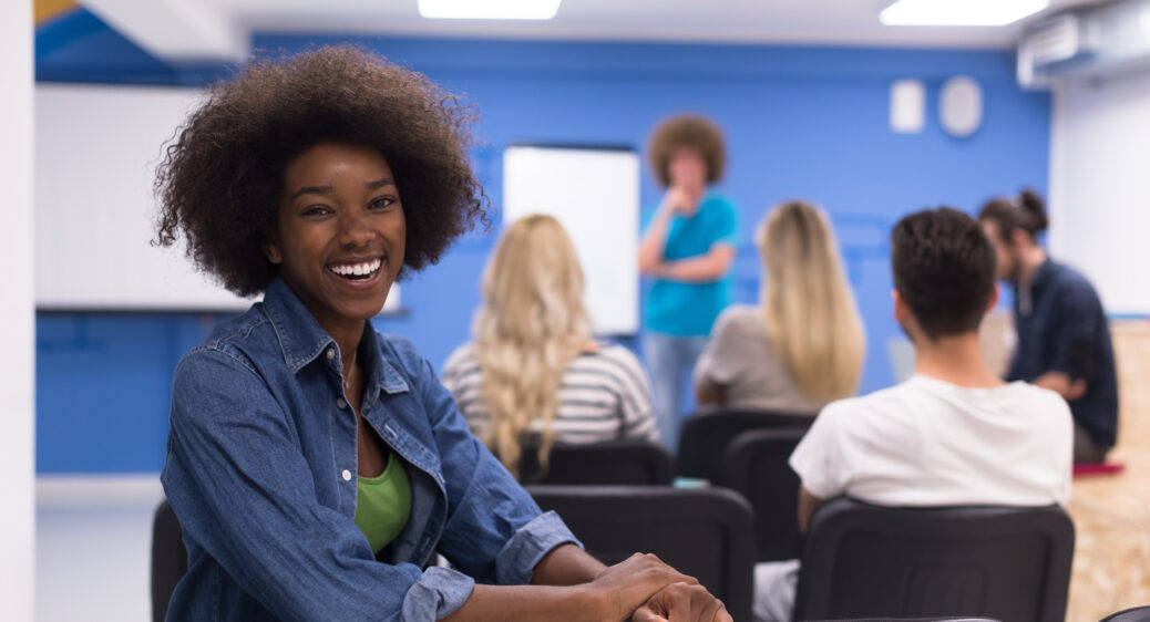 African American business woman facing the camera with a meeting in background