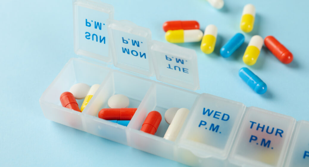 Image of plastic containers with pills on blue background