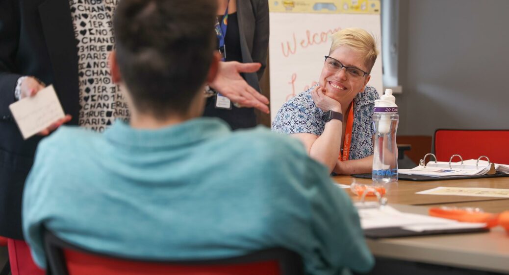 Smiling woman listens to person sitting in chair across from her