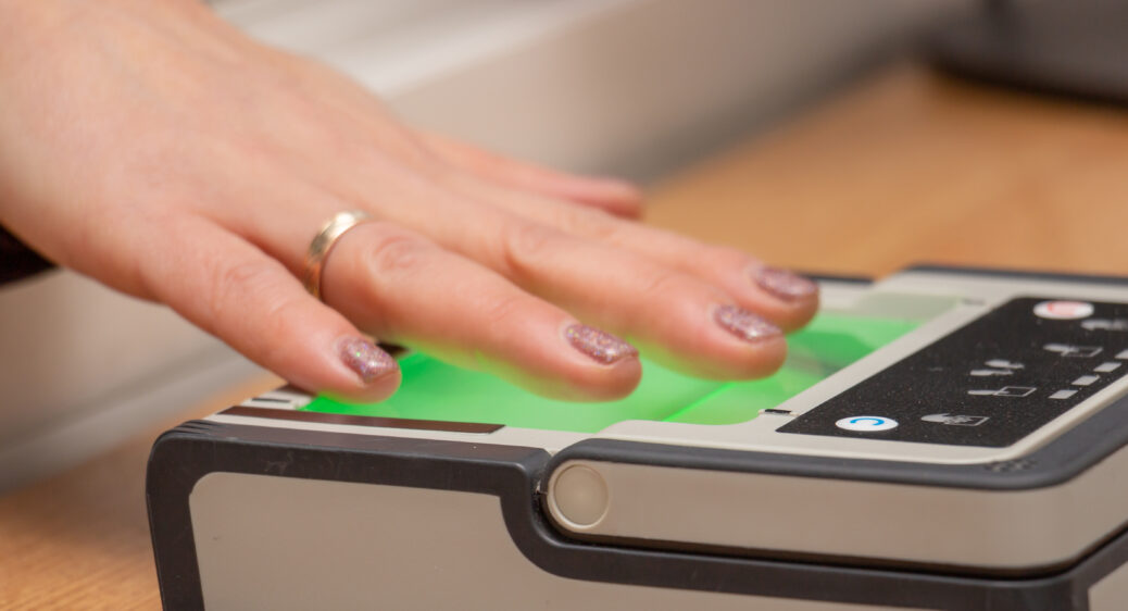 Female hand puts fingers to the fingerprint scanner.