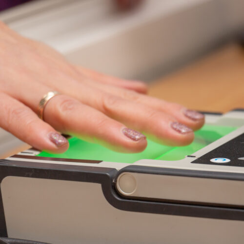 Female hand puts fingers to the fingerprint scanner.
